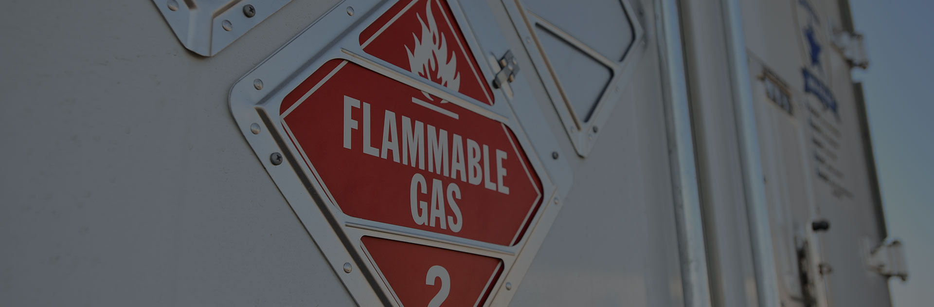 A flammable gas warning sign on the back panel of a truck.